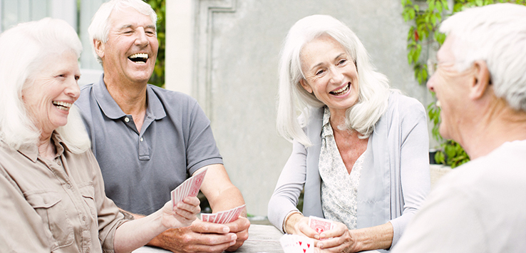 Senior couples playing cards on patio